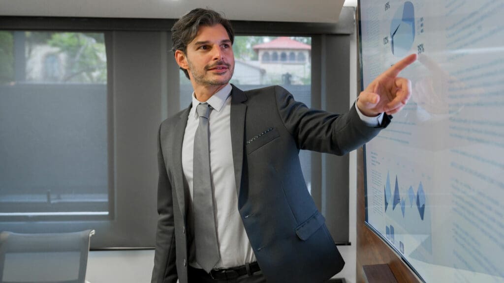 Businessman in conference room pointing to images on large screen